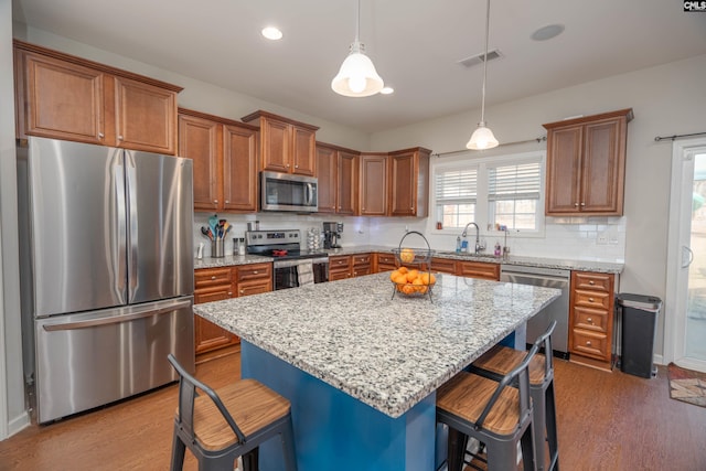 kitchen with a kitchen bar, appliances with stainless steel finishes, brown cabinets, and a center island