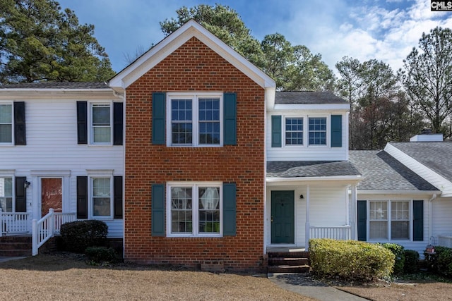 view of front of property featuring roof with shingles and brick siding