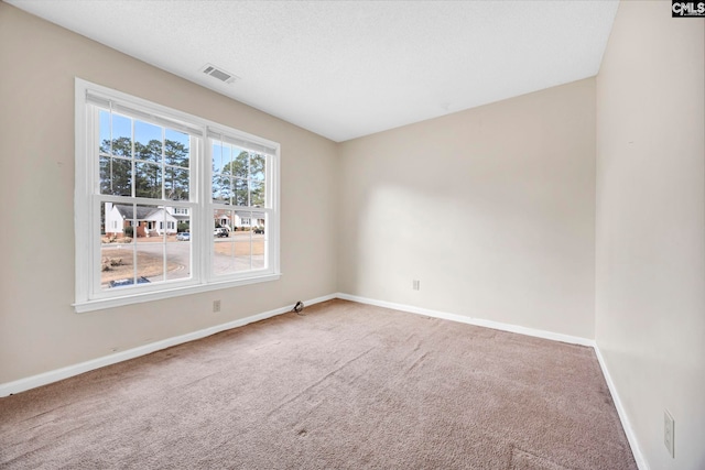 unfurnished room with carpet floors, visible vents, baseboards, and a textured ceiling