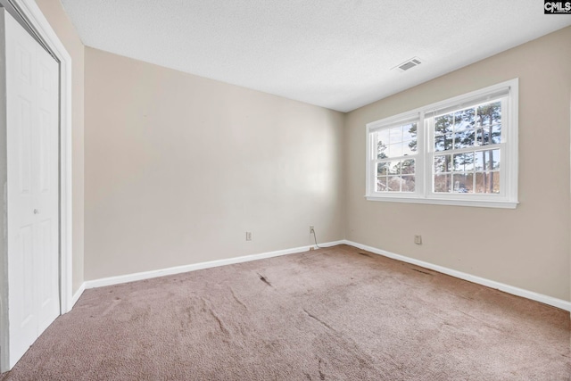 carpeted empty room with baseboards, visible vents, and a textured ceiling