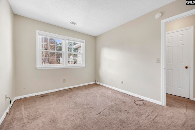 carpeted spare room with baseboards, visible vents, and a textured ceiling