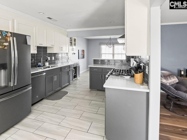 kitchen featuring stainless steel appliances, light countertops, white cabinets, and a sink