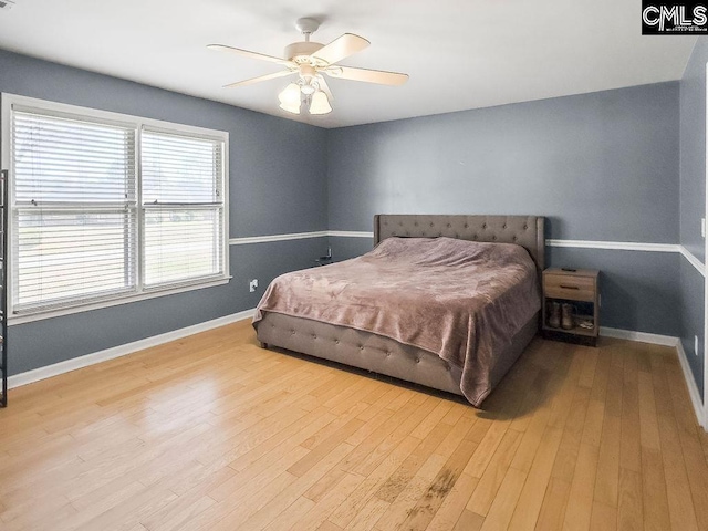 bedroom with light wood finished floors, ceiling fan, visible vents, and baseboards