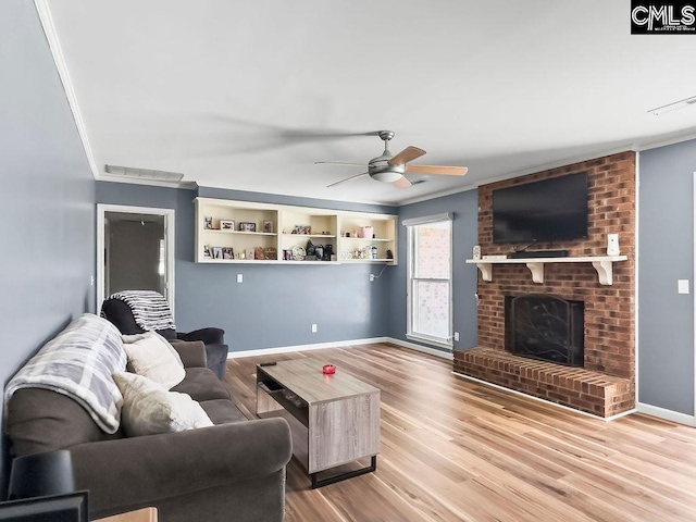 living room with a fireplace, crown molding, visible vents, and light wood finished floors