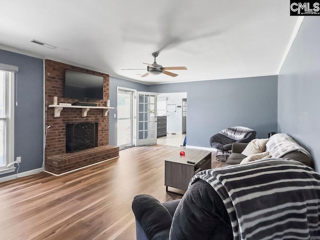 living area with light wood-style floors, a fireplace, and ornamental molding