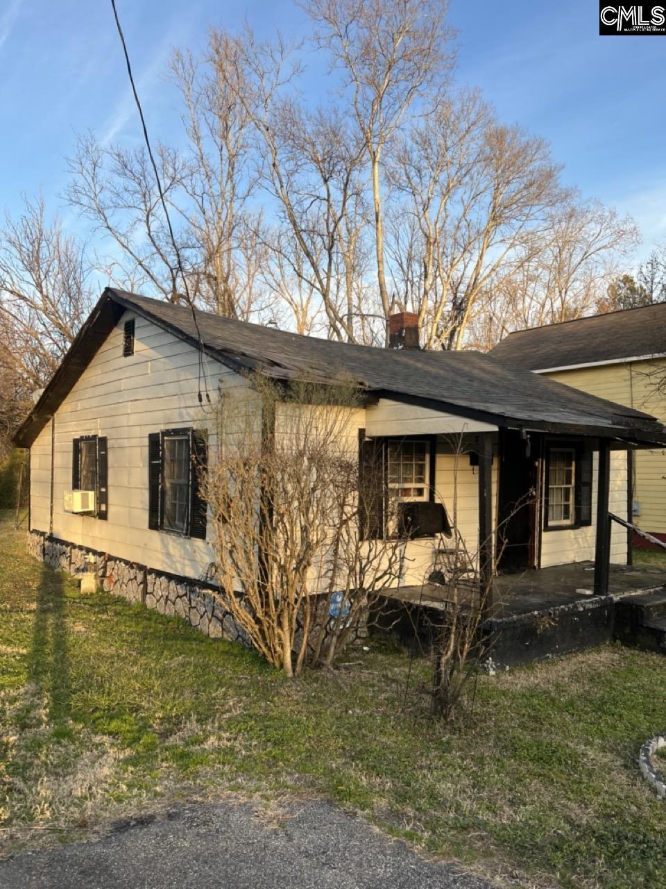 view of side of home featuring covered porch, a yard, and a chimney