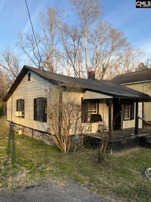 view of side of home featuring covered porch, a yard, and a chimney