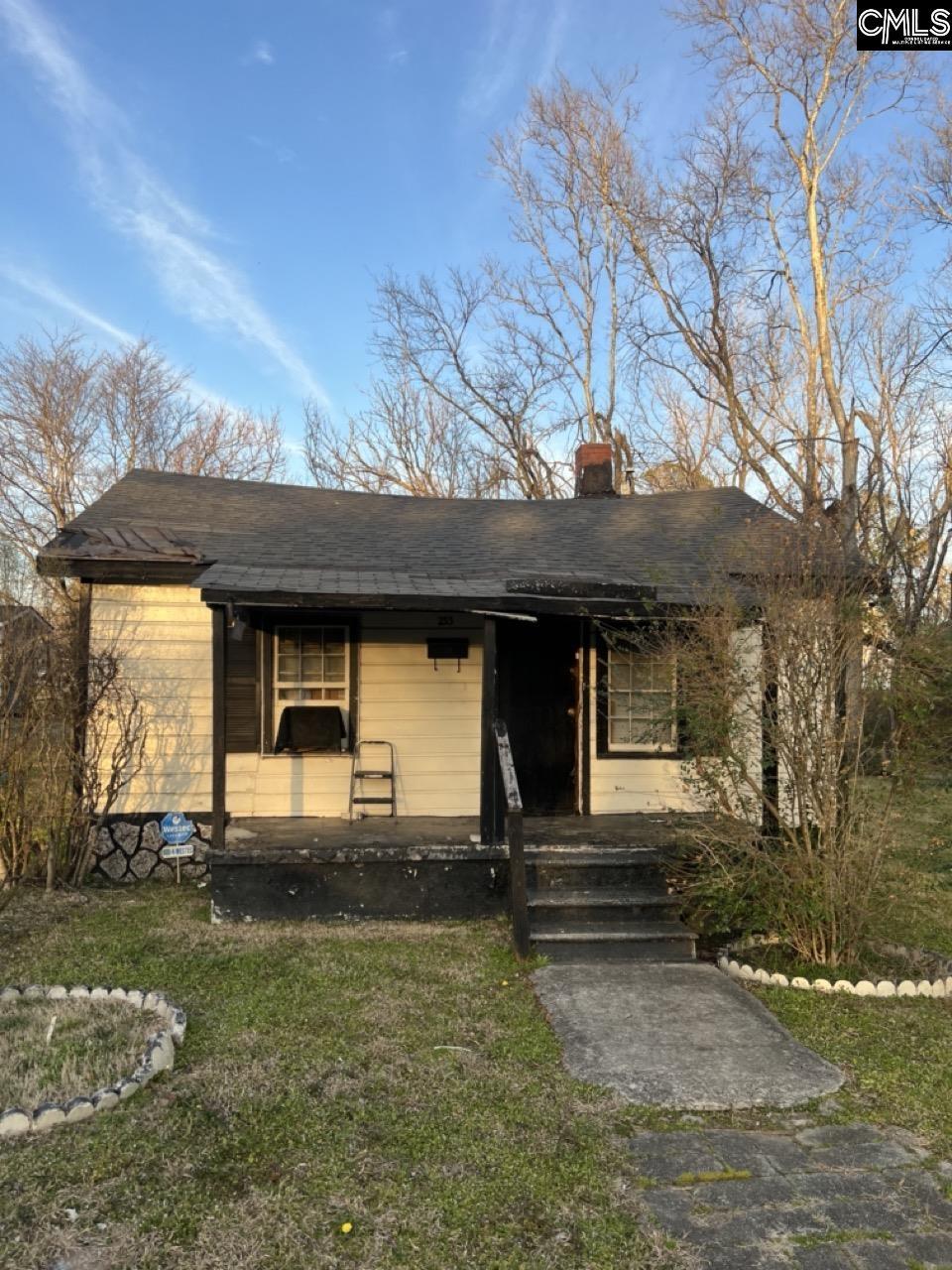 view of front of house with a porch, a front yard, and a chimney