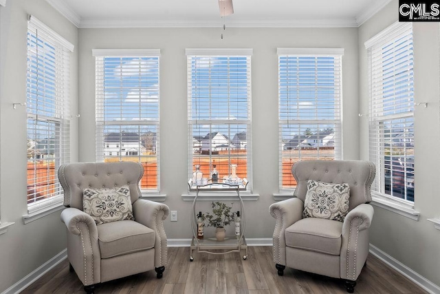 living area with ornamental molding, wood finished floors, and baseboards