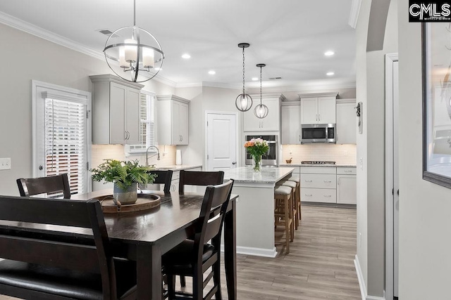 dining room with light wood finished floors, recessed lighting, ornamental molding, and an inviting chandelier