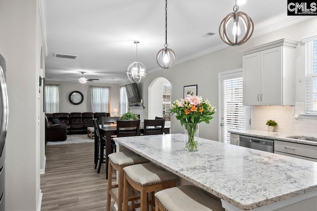 kitchen with a center island, arched walkways, hanging light fixtures, open floor plan, and white cabinets