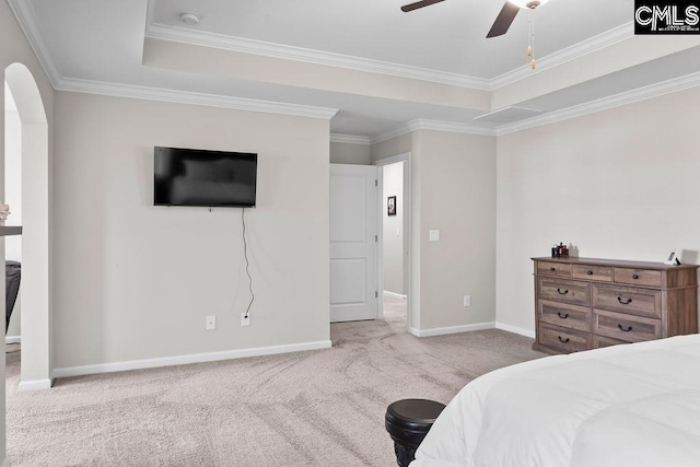 bedroom featuring a tray ceiling, light colored carpet, crown molding, and baseboards