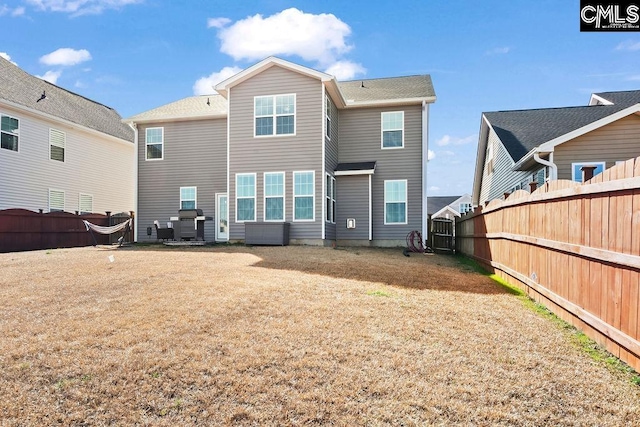 rear view of house featuring a fenced backyard and a yard