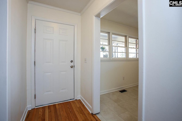 doorway to outside featuring light wood-style floors, baseboards, visible vents, and crown molding