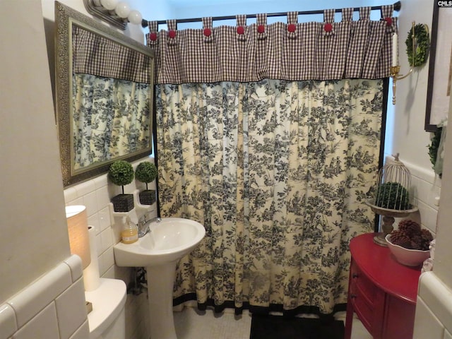 bathroom featuring tile walls and toilet