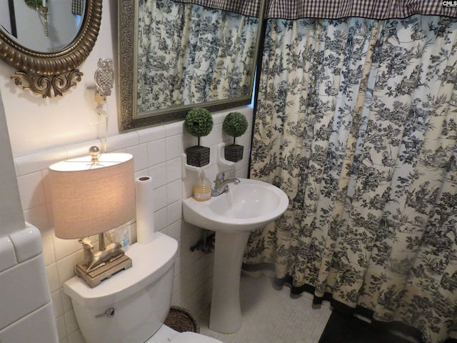 bathroom featuring toilet, a shower with shower curtain, and tile walls