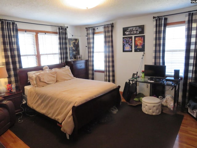 bedroom with a textured ceiling and wood finished floors