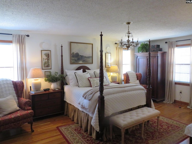 bedroom featuring light wood-style floors, a notable chandelier, and a textured ceiling