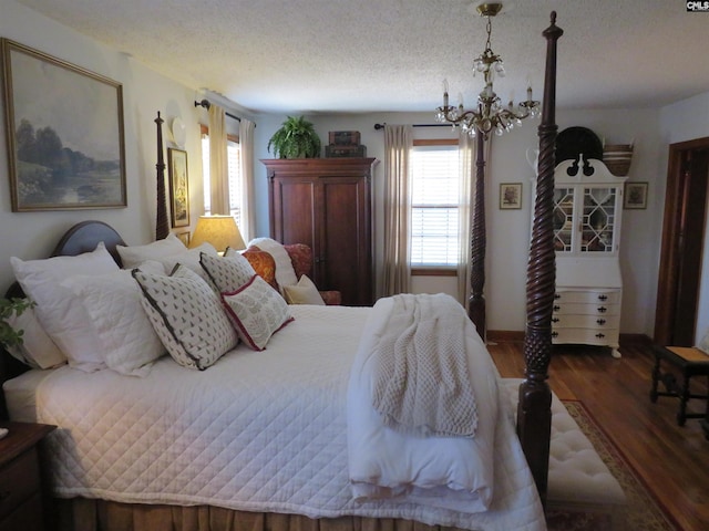 bedroom with a chandelier, dark wood finished floors, and a textured ceiling