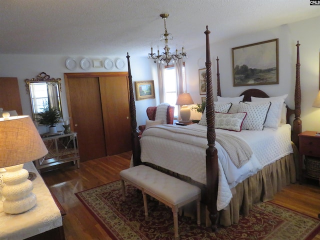 bedroom with a closet, a notable chandelier, dark wood finished floors, and a textured ceiling