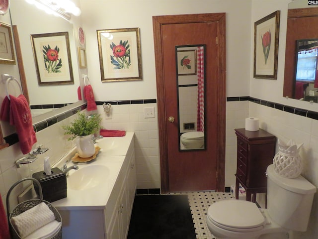 full bathroom with a sink, tile walls, toilet, and double vanity