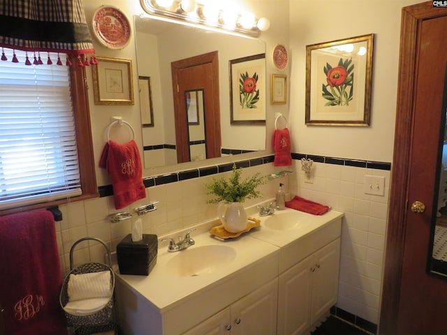 full bathroom with double vanity, wainscoting, a sink, and tile walls