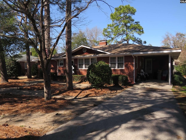 ranch-style house with concrete driveway, brick siding, and a chimney