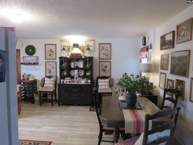 dining room featuring a textured ceiling and light wood-style flooring