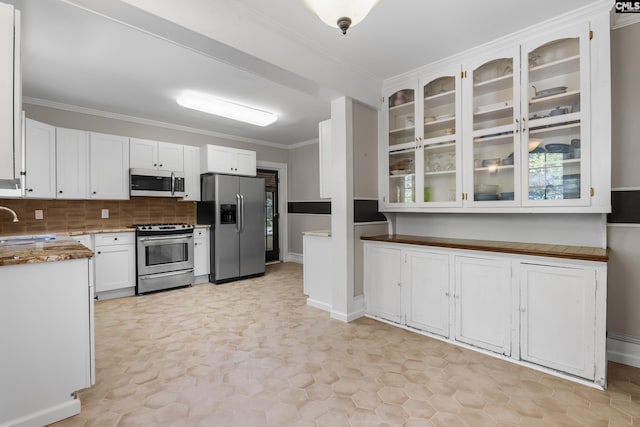 kitchen with glass insert cabinets, stainless steel appliances, crown molding, white cabinetry, and a sink