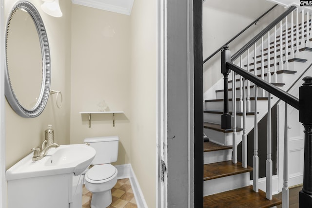 bathroom with toilet, a sink, baseboards, and crown molding