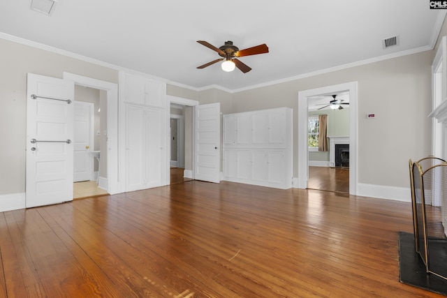 unfurnished living room featuring hardwood / wood-style flooring, a fireplace, visible vents, and crown molding