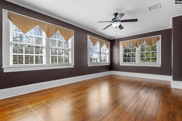 spare room featuring a healthy amount of sunlight, visible vents, baseboards, and hardwood / wood-style floors