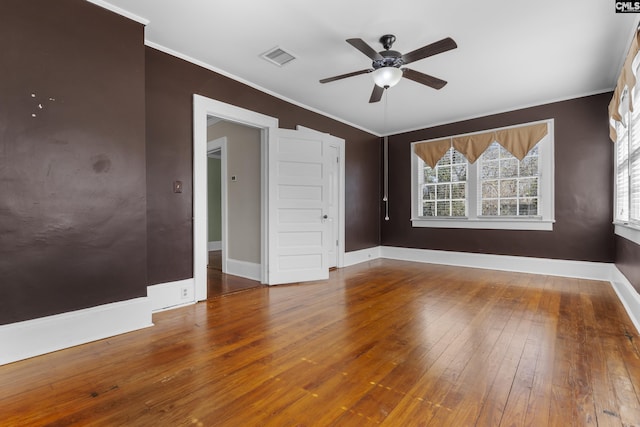 empty room with visible vents, crown molding, baseboards, and hardwood / wood-style flooring