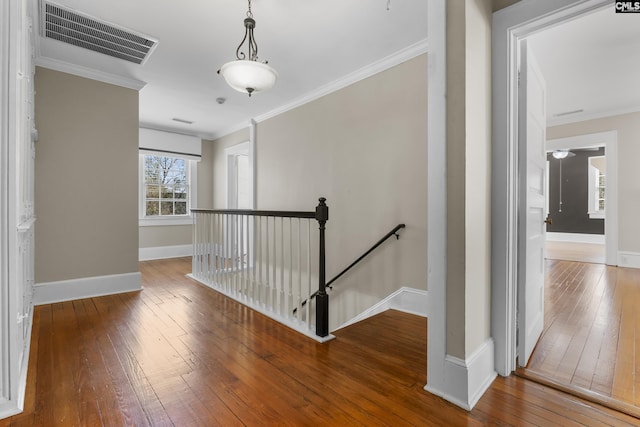 hall with visible vents, an upstairs landing, baseboards, ornamental molding, and wood-type flooring