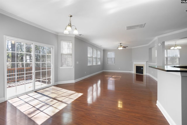 unfurnished living room with visible vents, dark wood-style floors, a fireplace with flush hearth, crown molding, and ceiling fan with notable chandelier