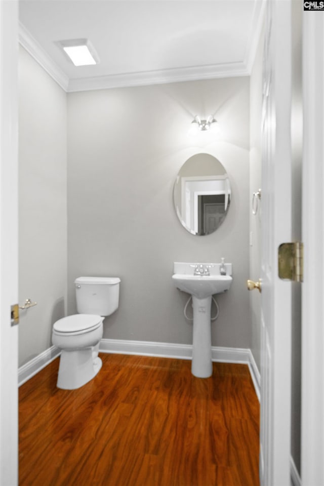 bathroom with baseboards, crown molding, toilet, and wood finished floors