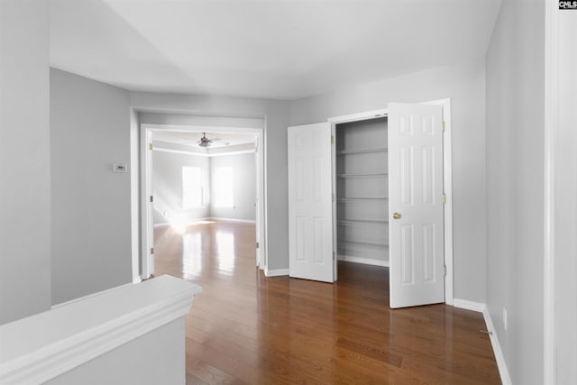 unfurnished bedroom with a closet, dark wood-style flooring, and baseboards