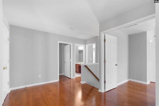 spare room with baseboards, visible vents, and wood finished floors