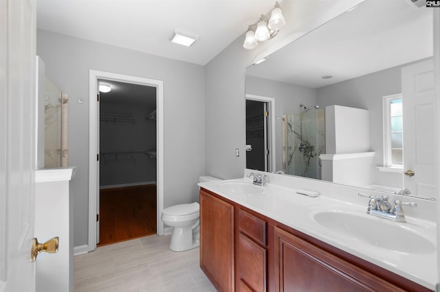 full bathroom with toilet, a sink, a marble finish shower, and double vanity