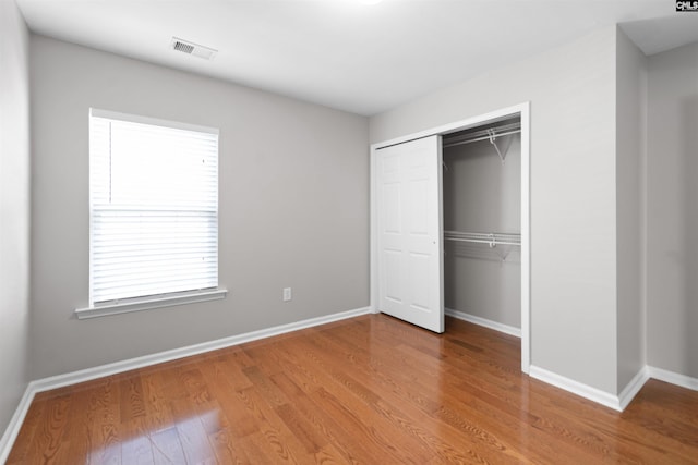 unfurnished bedroom with visible vents, baseboards, a closet, and wood finished floors