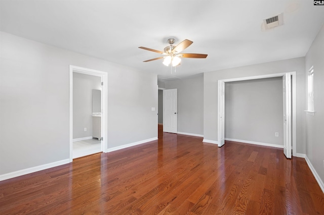 unfurnished bedroom featuring dark wood-type flooring, a ceiling fan, visible vents, and baseboards