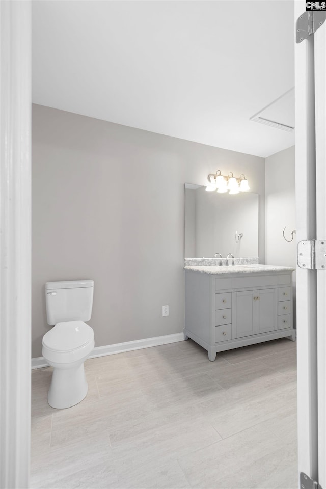 bathroom featuring baseboards, vanity, toilet, and wood finished floors