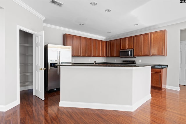 kitchen with stainless steel appliances, visible vents, an island with sink, dark countertops, and dark wood finished floors