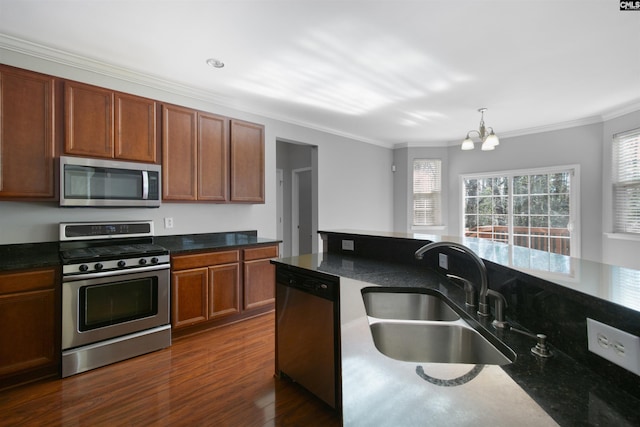 kitchen featuring a sink, ornamental molding, appliances with stainless steel finishes, dark wood finished floors, and decorative light fixtures