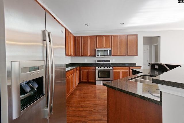 kitchen with stainless steel appliances, ornamental molding, a sink, and brown cabinets