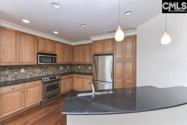 kitchen featuring dark wood-style flooring, pendant lighting, stainless steel appliances, decorative backsplash, and a sink