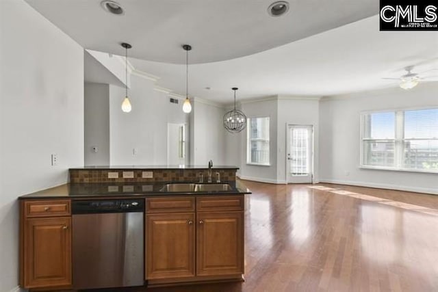 kitchen featuring brown cabinets, dark countertops, stainless steel dishwasher, open floor plan, and a sink