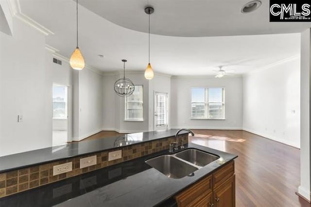 kitchen with a sink, open floor plan, dark countertops, dark wood finished floors, and pendant lighting