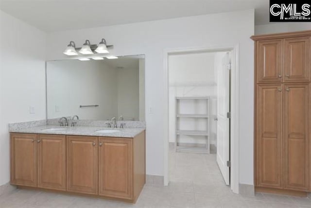 full bath with double vanity, a spacious closet, and a sink