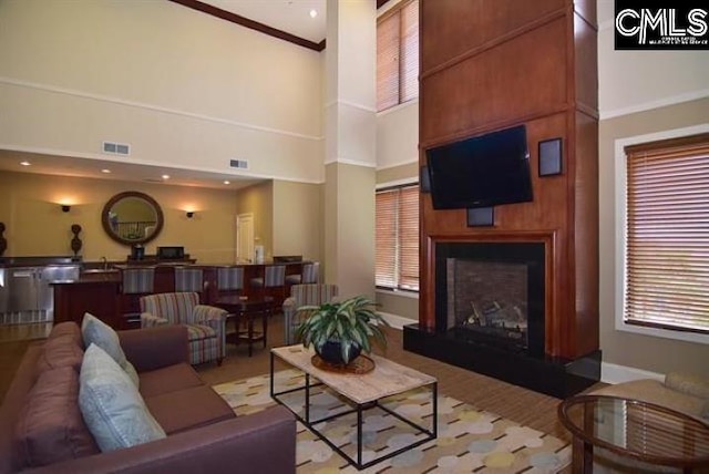 living area with a high ceiling, visible vents, and a fireplace with raised hearth